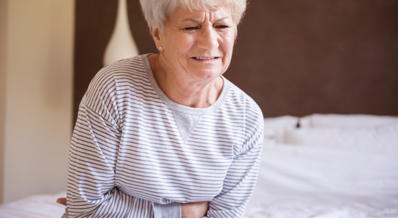 Elderly woman is hugging her stomach feeling uneasy