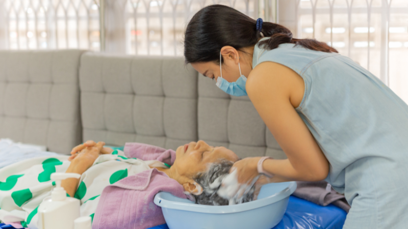 a caregiver washing hair for elderly woman