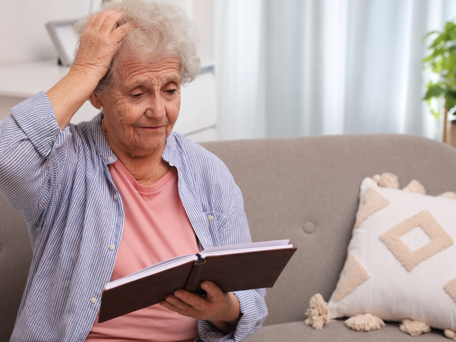 senior with dementia sitting on sofa and reading book