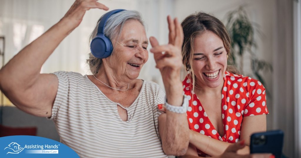 Caregiver and a senior woman smiling while listening to music