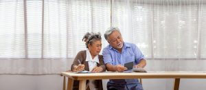 An older couple sits together at a table, carefully reviewing financial documents and using a calculator with focused expressions. This image reflects the important process of calculating benefit limits before activating long-term care insurance in Murray, UT. Understanding your maximum lifetime benefit and daily limits is a critical part of making the most of your LTCI in Murray, UT without outliving your coverage. 