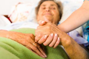 A caregiver gently holds the hand of an elderly woman resting in bed, capturing the tenderness and dedication that goes into daily caregiving. Respite care in Murray, UT ensures that seniors continue to receive this level of compassionate attention even when their primary caregiver needs a break. Respite care for seniors in Murray, UT provides families with the peace of mind that their loved one is in good hands.