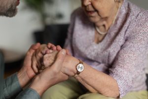 A caregiver gently holds the hands of a smiling elderly woman, capturing the tenderness and trust at the heart of quality dementia care near me Murray, UT. This kind of compassionate presence — whether through family or a professional senior caregiver in Murray, UT — can make an enormous difference for those navigating the Medicare GUIDE program Murray, UT and seeking structured, coordinated support. 