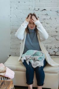 A woman sits with her head in her hands, visibly drained, a crumpled blanket in her lap, capturing the quiet exhaustion behind caregiver burnout in Murray, UT. Respite care near me and respite care Murray offer a way to step back and recover before burnout in caregivers Murray, UT deepens. 