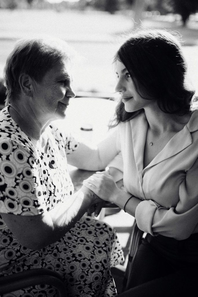 An adult daughter sits close and holds her elderly mother's hands during a warm, unhurried visit, the two sharing a quiet look that speaks to the emotional weight of caring for an aging parent. Moments like these are what 24/7 home care helps preserve, giving families presence instead of worry. At home caregivers in Murray, UT provide caregiver services that let seniors stay safely and comfortably in familiar surroundings.