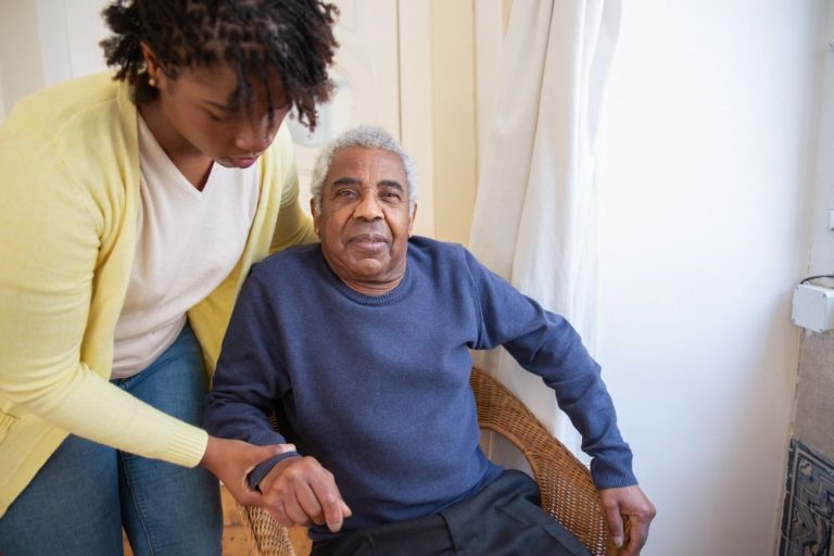 Caregiver assisting an older man in his chair at home