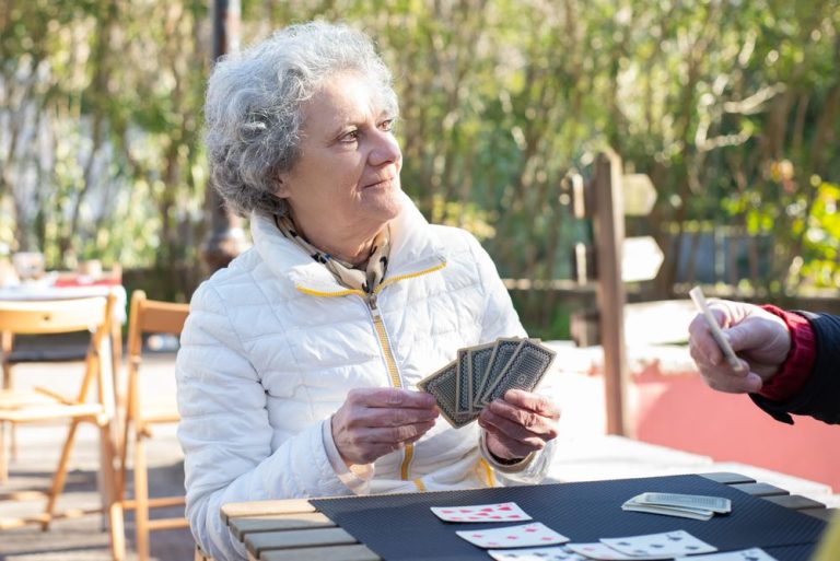 Smiling older woman playing cards on a sunny patio
