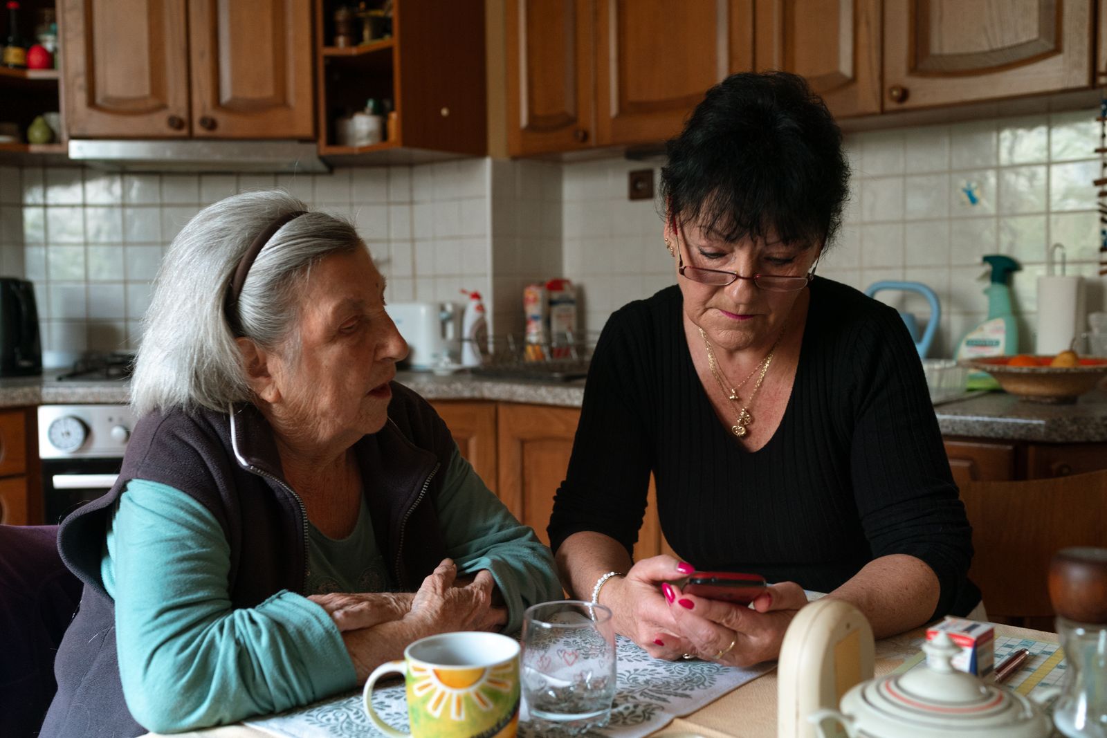 Caregiver and older woman sharing tea at the kitchen table