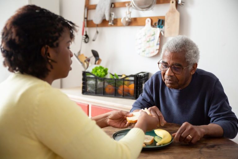 Caregiver serving a home-cooked meal to an older man