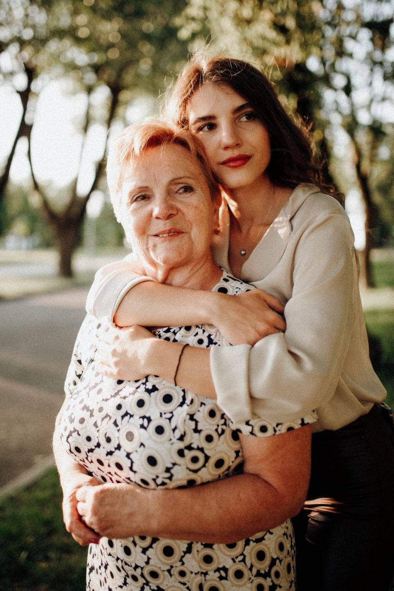 Adult daughter hugging her smiling mother outdoors