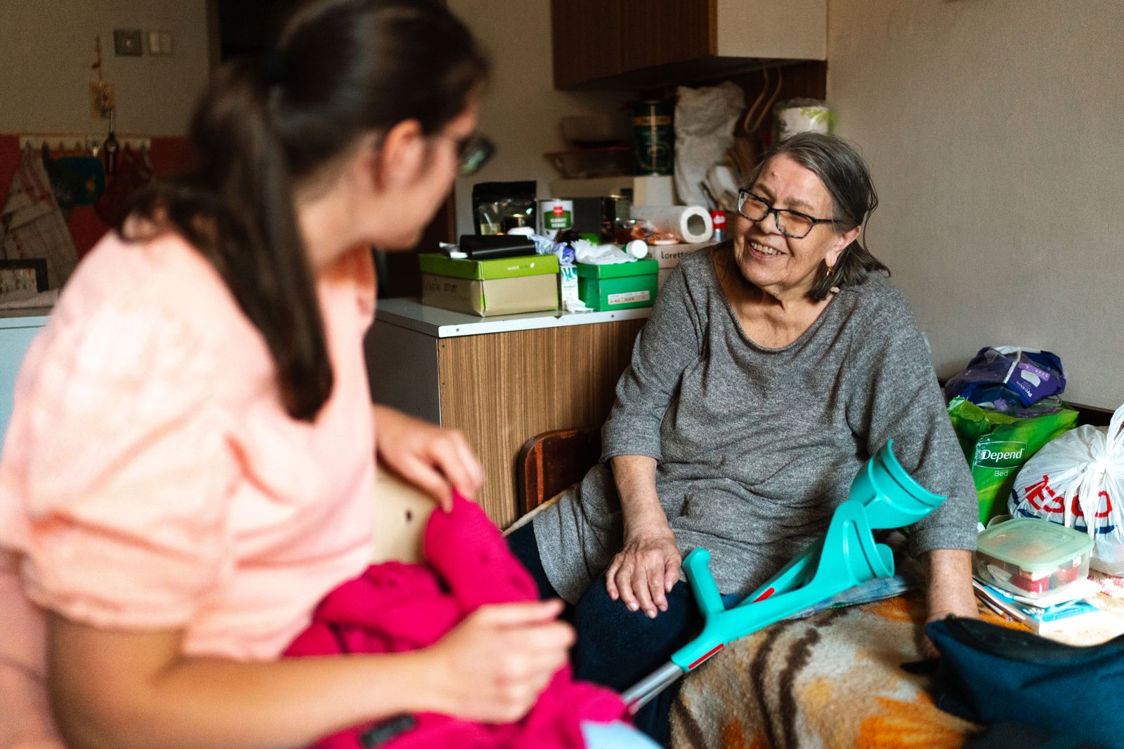 Caregiver helping an older woman get dressed at home
