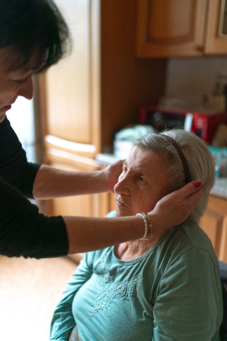 Caregiver gently helping an older woman with skin care