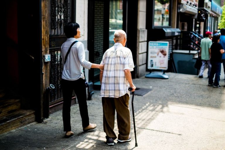 Caregiver walking beside an older man using a cane