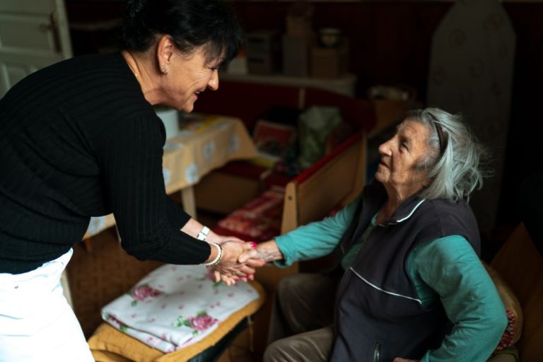 Caregiver warmly greeting an older woman at home