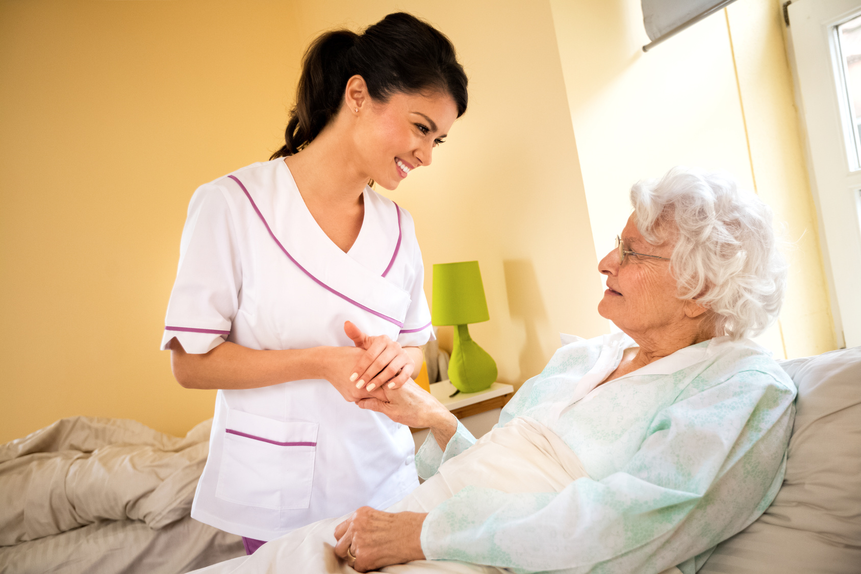 Beautiful nurse holding hand of old senior patient and comfort her