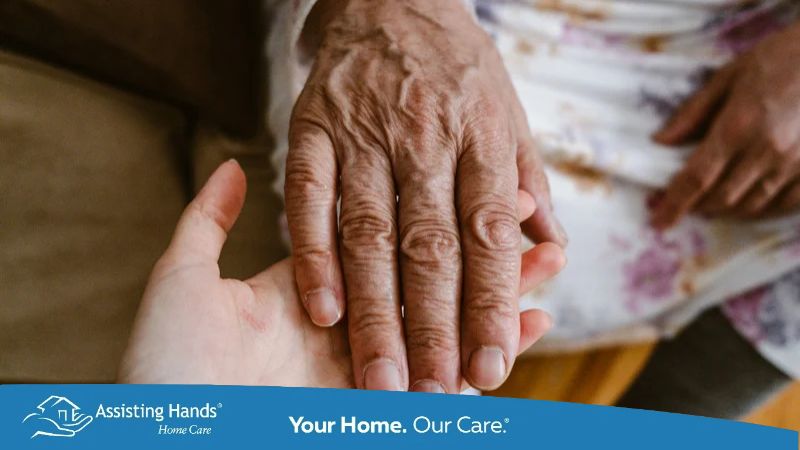 Elderly woman holding hands with her caregiver, showing compassion and support.