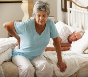 Senior Woman Suffering From Backache Getting Out Of Bed