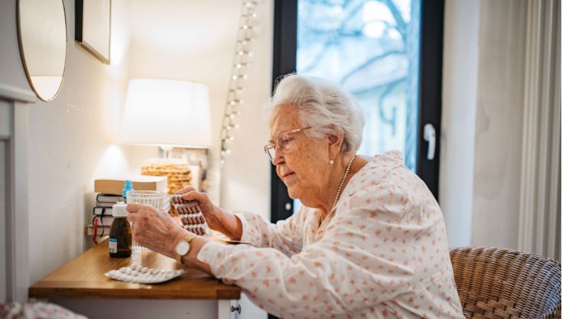 Elderly woman looking confused while trying to determine which medication to take