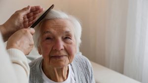 caregiver brushing senior woman's hair who has dementia
