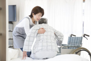 Home care provider helping senior out of bed