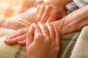caregiver hand resting on hand of a senior