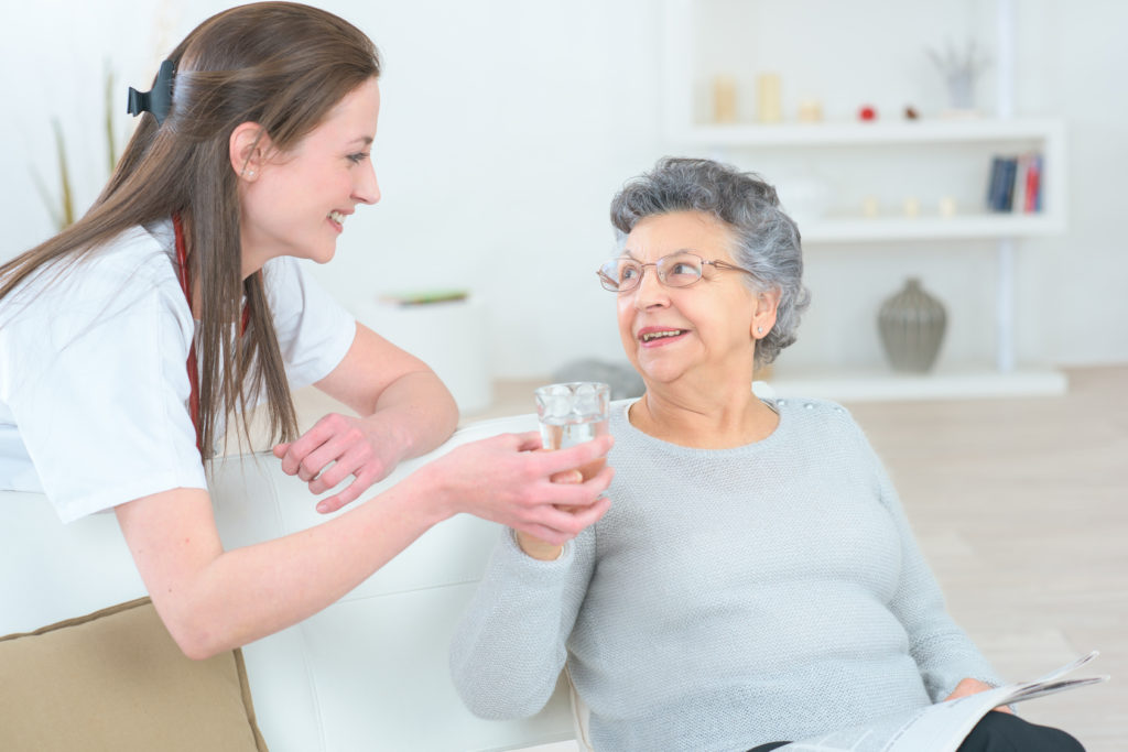 Caregiver-Giving-Water-to-Elderly-Woman