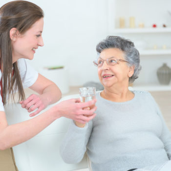Caregiver-Giving-Water-to-Elderly-Woman