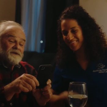 Elderly Man and Caregiver Talking to Daughter on the Phone
