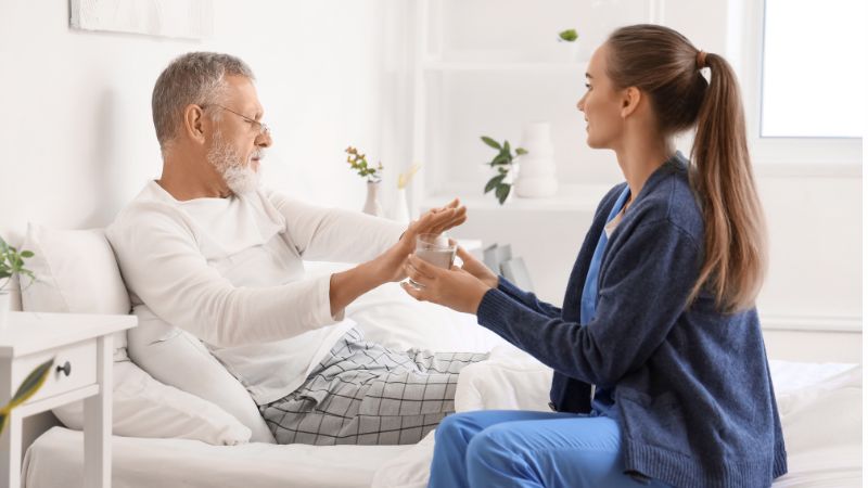 senior man refusing to take medicine from caregiver