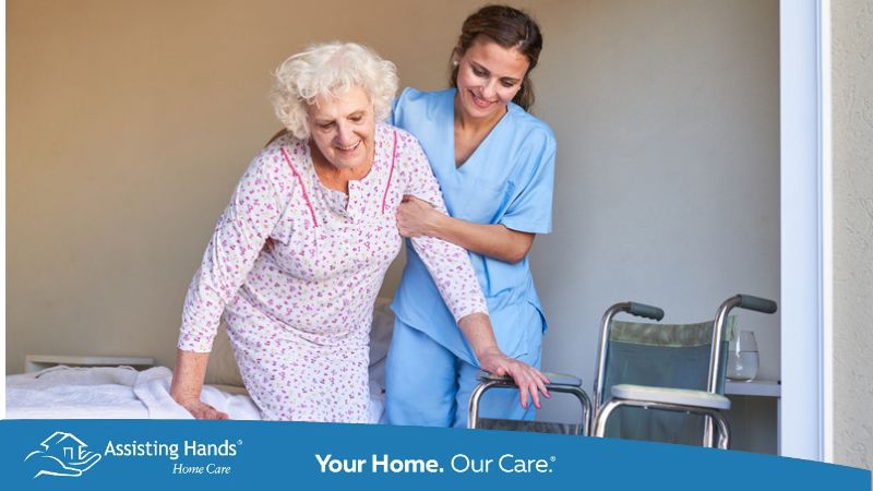 caregiver helping senior woman getting out of bed
