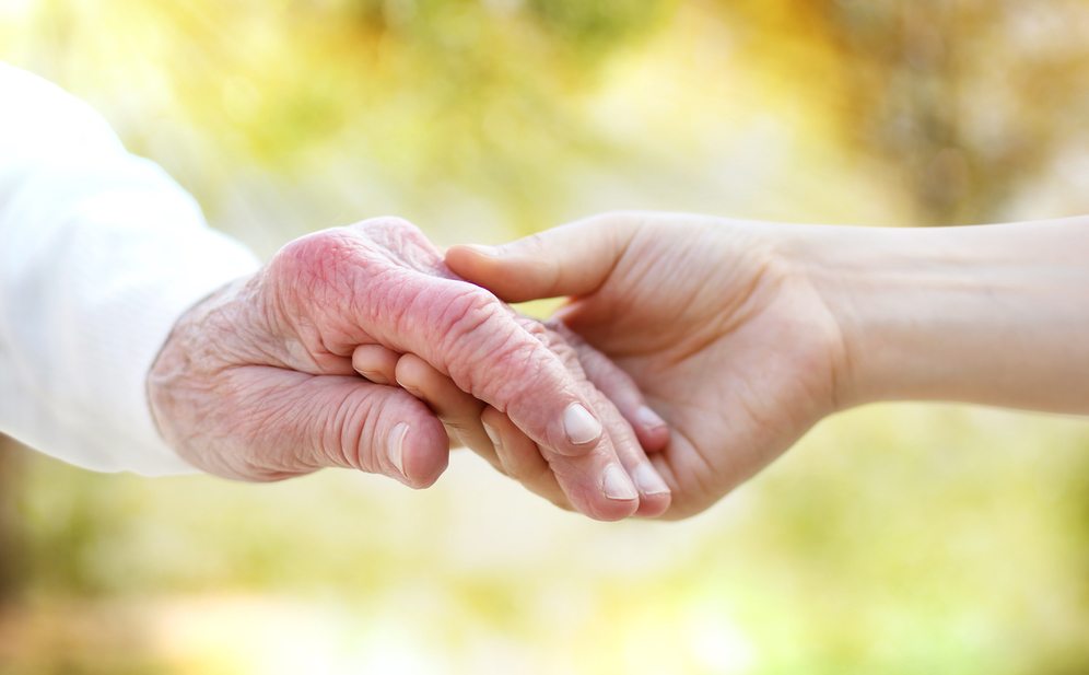 Caregiver holding senior's hand Hospice Supplemental Care Assistance in Pembroke Pines, FL