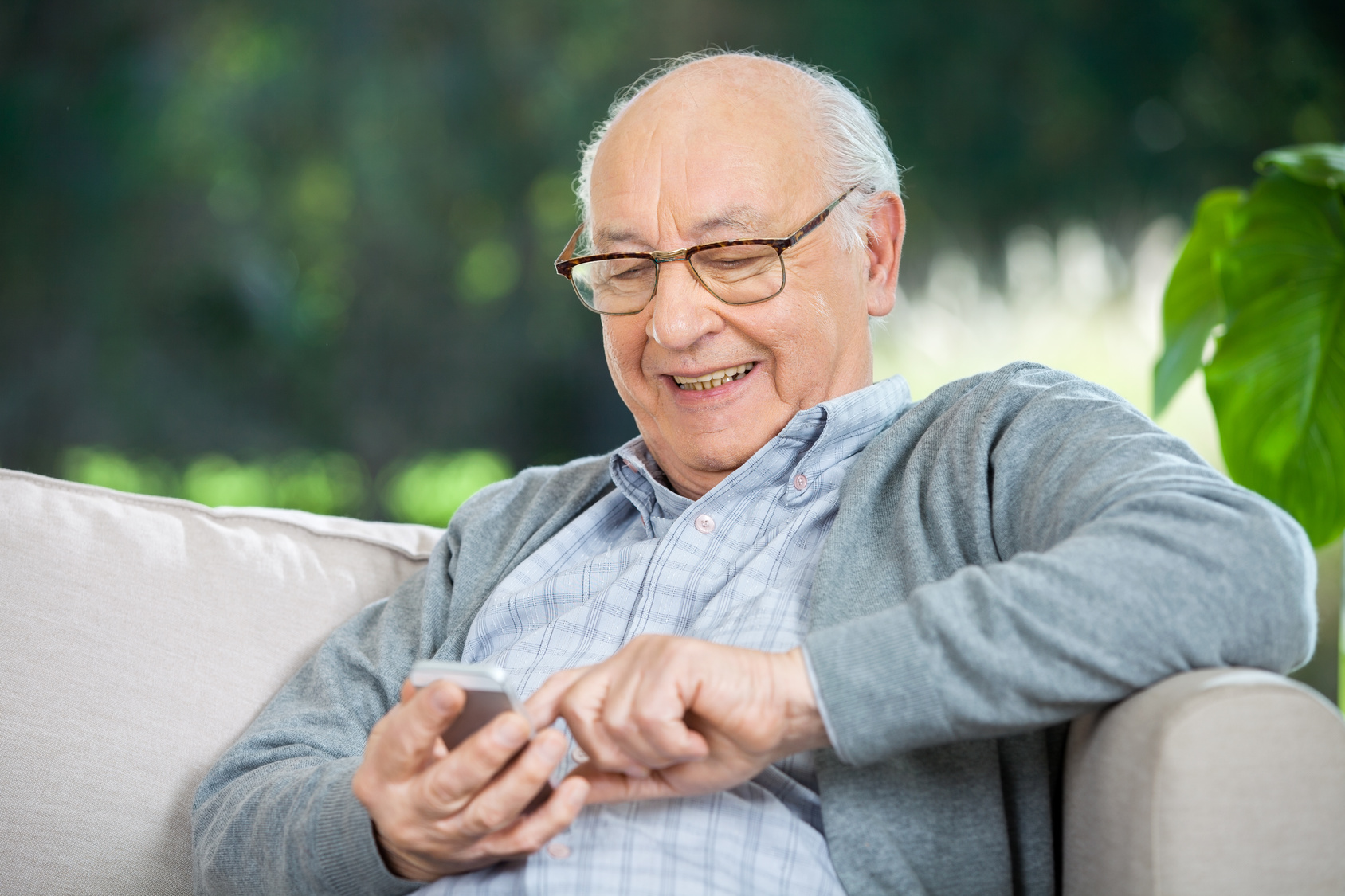 Smiling Senior Man Text Messaging Through Mobilephone