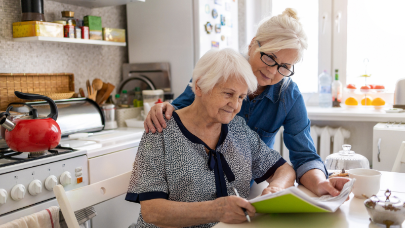 Senior Woman and Daughter doing Paperwork - Assisting Hands Home Care | Scam Prevention for Seniors