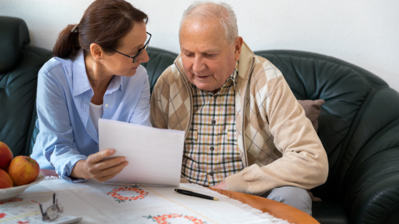 Young woman and elderly man reviewing paperwork