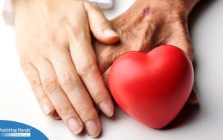 An old hand and a young hand with a heart represent caregiving.
