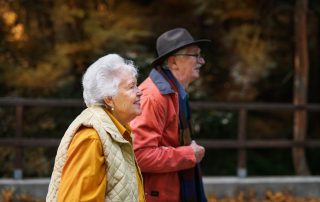 Happy senior couple in autumn clothes walking in park together.