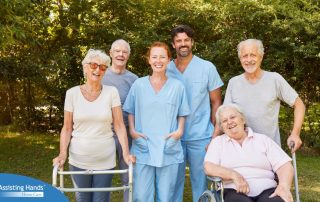 2 caregivers and seniors smile while in a group representing how caregivers can facilitate socialization.