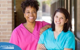 2 caregivers smile representing the good attitude that can allow home care professionals to collaborate.