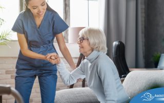 A caregiver demonstrates her caregiver skills by helping an older adult get up.