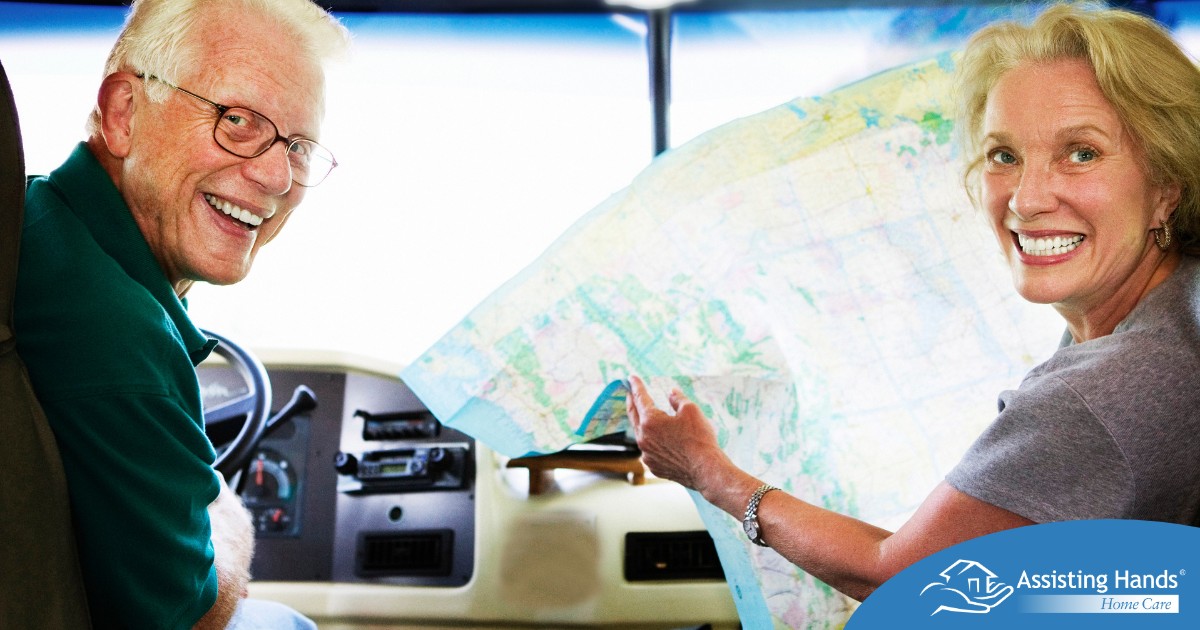 An older couple looks back smiling from the front of an RV, representing how day trips for seniors can help boost the mood of everyone.