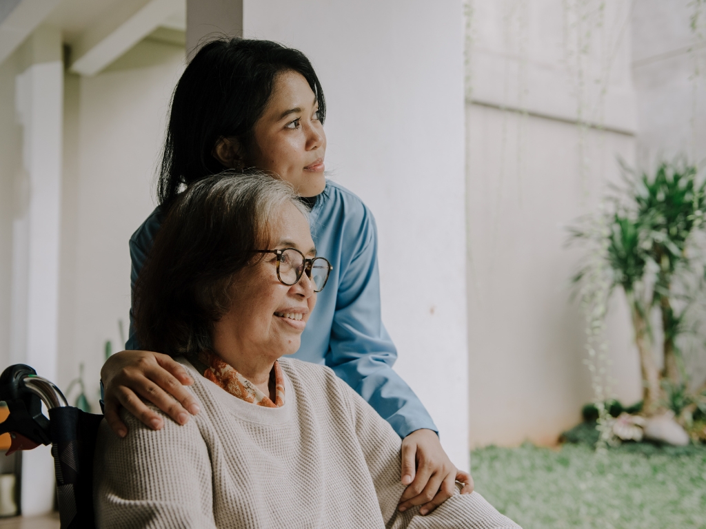 A caregiver offers support to an elderly woman in a wheelchair, symbolizing compassionate Alzheimer’s and Dementia Care in Bedford.