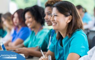 Several students in scrubs happily attend a class, representing caregiver training.