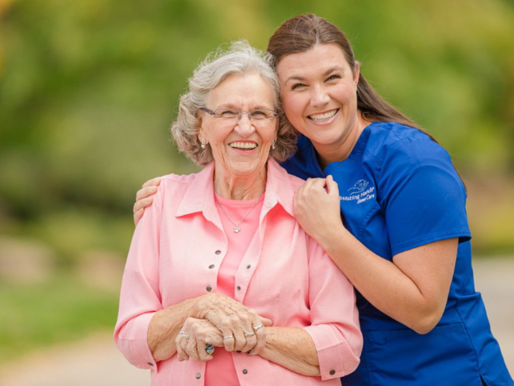 A smiling caregiver embraces an elderly woman outdoors, representing veteran care in Bedford with compassionate, supportive home care services.