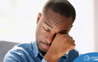 A man tiredly rubs his eyes, representing the exhaustion that can come with family caregiving.