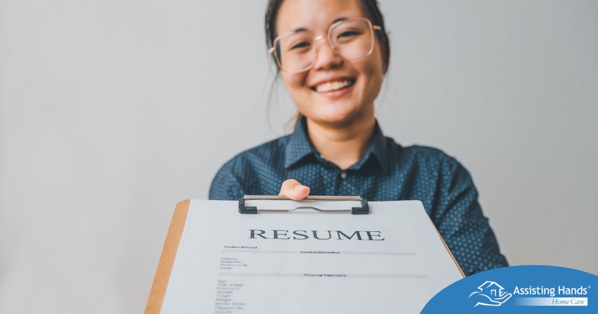 A woman happily hands in a resume, representing a successfully written caregiver resume.