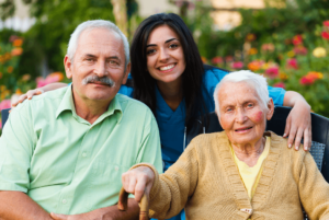 smiling elderly couple and a caregiver