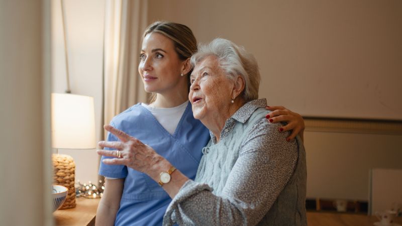 caregiver giving warmth and comfort to senior woman with dementia at home