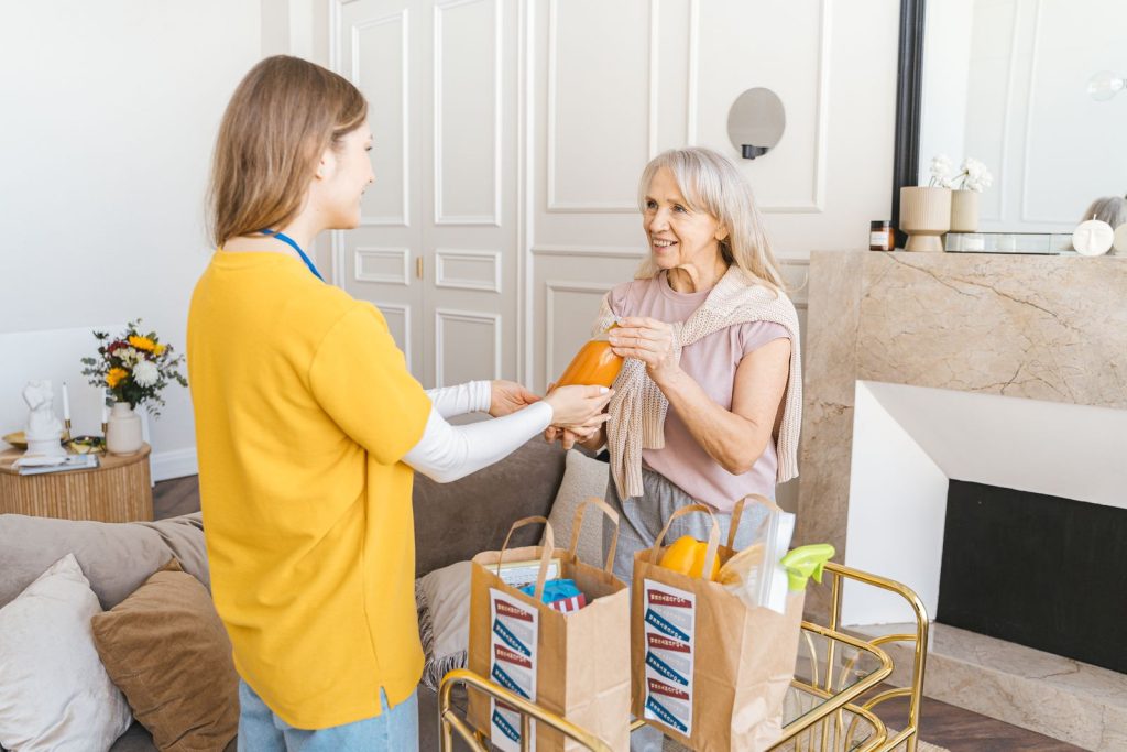 Caregiver bringing groceries to a senior woman at home