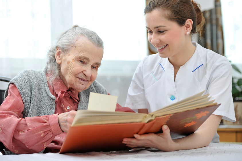 Dementia Care - Personal Care and Companionship - elderly woman reading a book with a caregiver