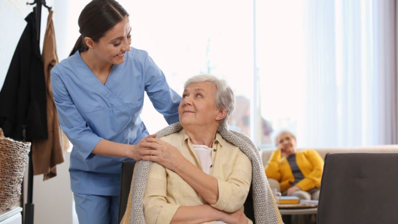 caregiver-is-placing-a-warm-scarf-on-elderly-woman-who-is-feeling-cold